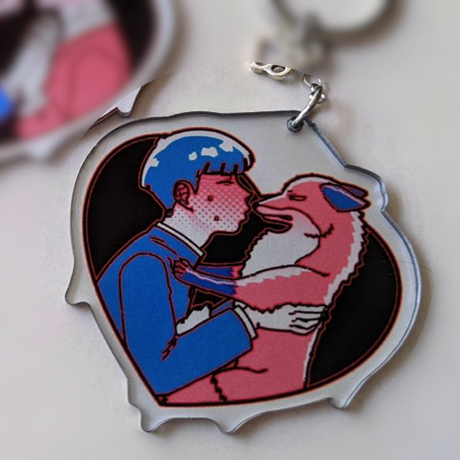 A photo of a charm made of see-through acrylic with a solid silver coating as background color. The design is of two characters, a human and a fox. The human character has his eyes closed, leaning for a kiss. The fox is pushing away from the human with its paws, looking upset.