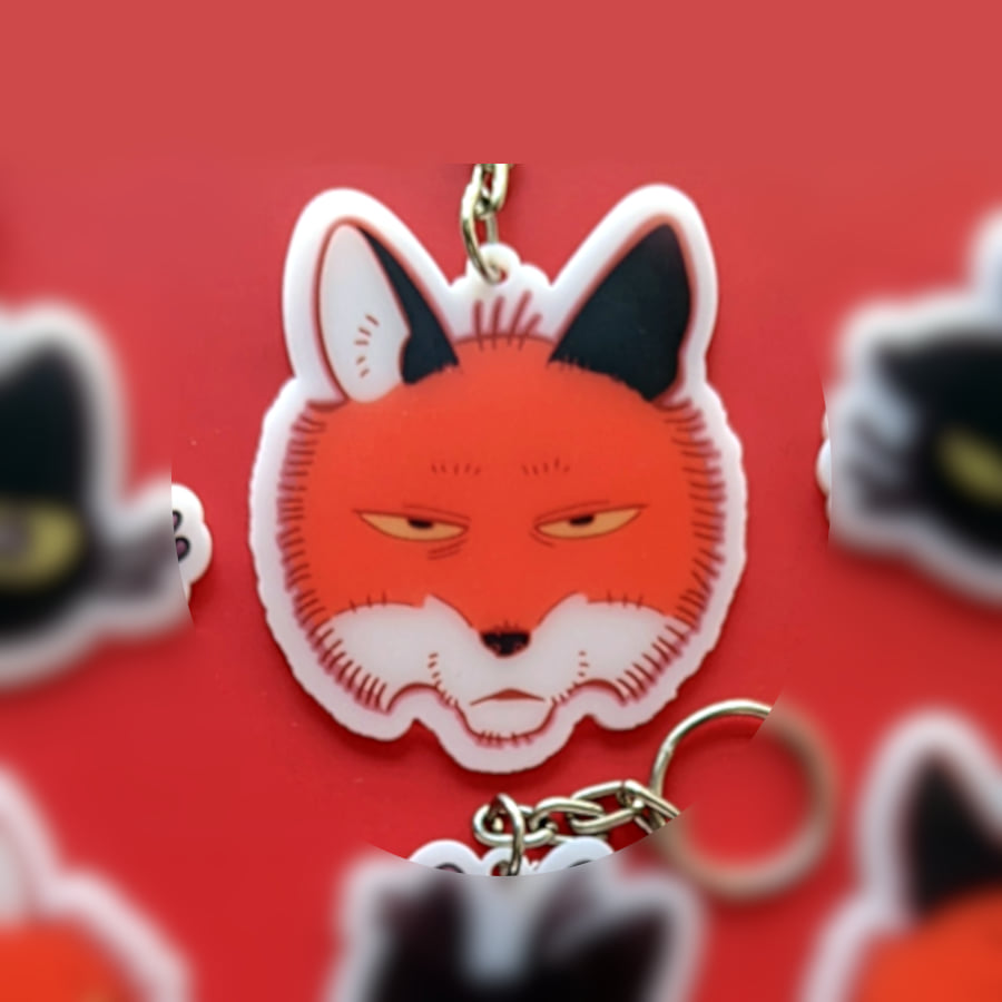 A photo of a charm made of opaque white acrylic. There design is a fox with a blank expression.